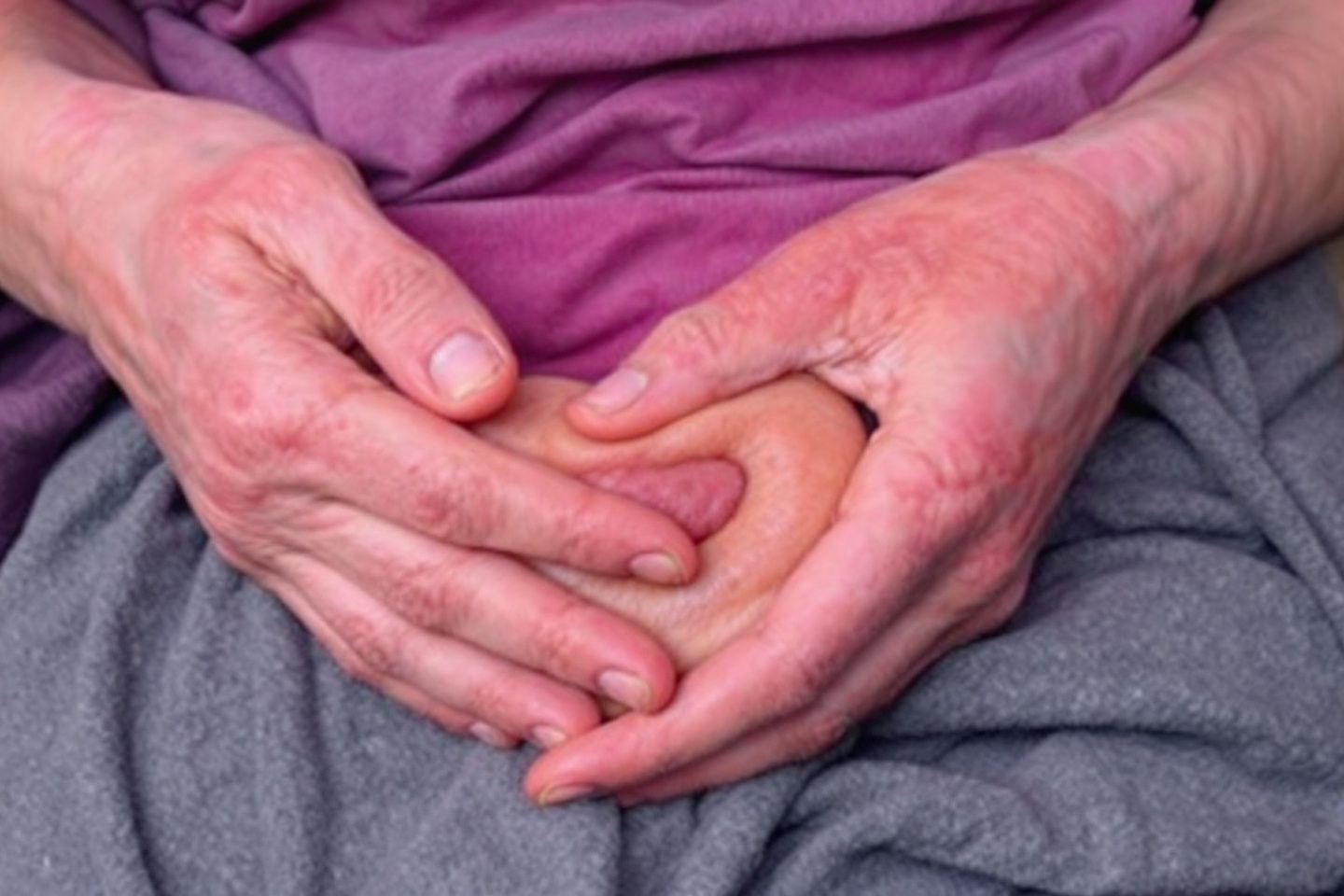Mains ridées et rouges sur un tissu gris et violet
