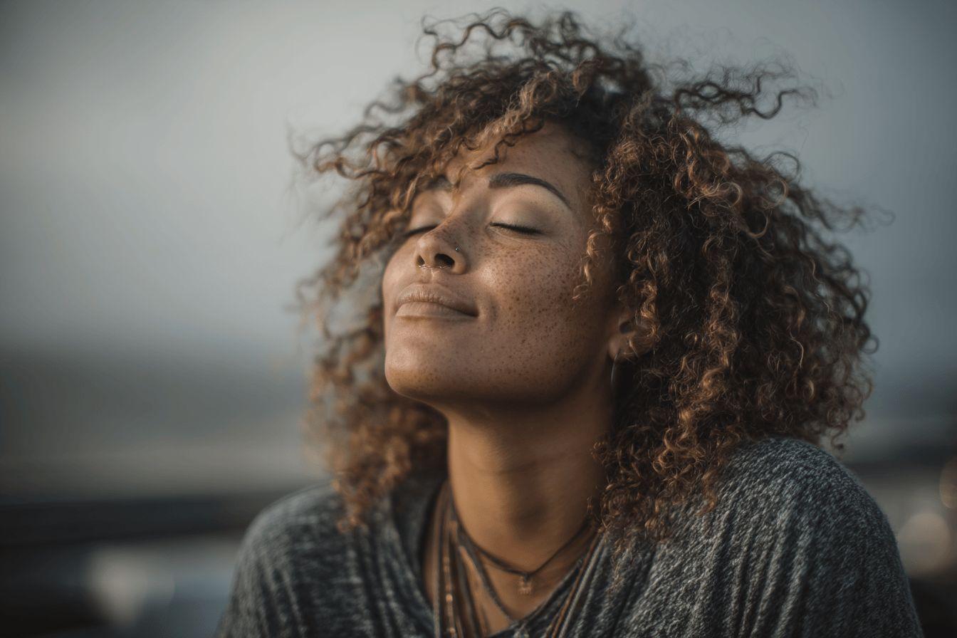 Femme aux cheveux bouclés les yeux fermés, visage apaisé